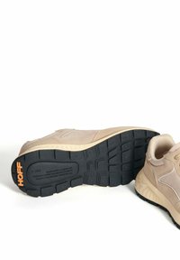 Zapatillas deportivas de color beige claro con parte superior de ante y malla, suela exterior de goma negra texturizada, con la marca HOFF en naranja en el talón.