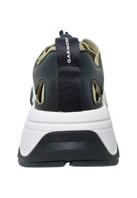 Black and white sneaker featuring a textured sole, mesh side panels, and a prominent fabric heel tab with the brand name "GARMONT."
