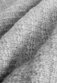 Grey knitted fabric with a soft texture, featuring a subtle herringbone pattern. The material is fluffy with a mix of light and dark grey fibers.