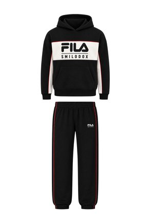 Deux enfants portant des sweats à capuche et pantalons noirs FILA assortis avec des baskets blanches, debout côte à côte, l’un reposant le bras sur l’épaule de l’autre.
