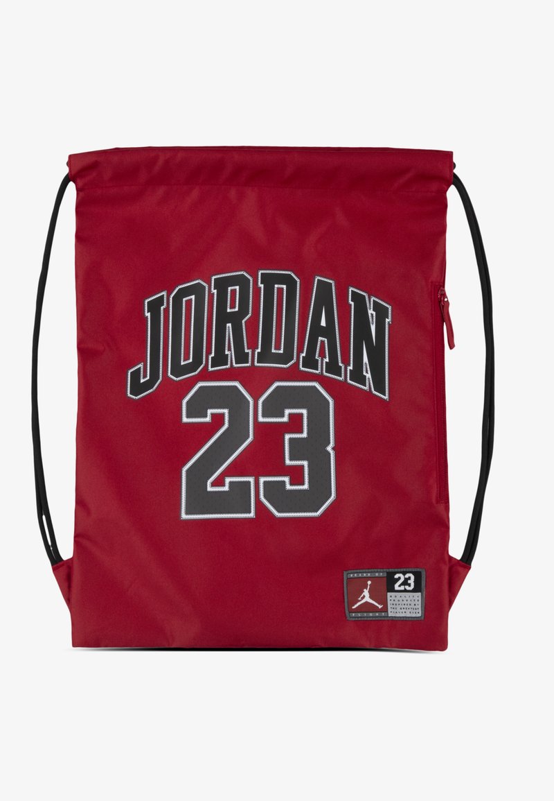Rød nylon ryggsekk med svarte snorer, med "JORDAN 23" trykt i grått på forsiden og et lite logomerke nederst til høyre.