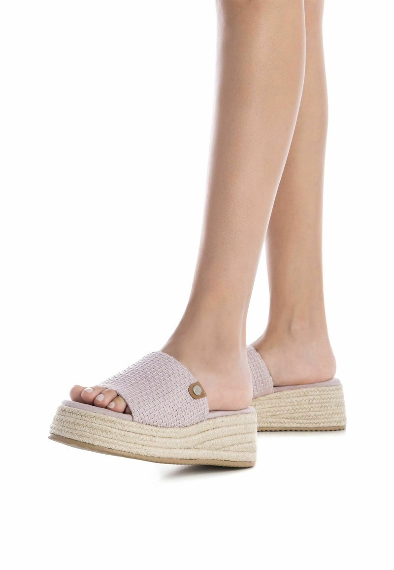 Sandalias de plataforma tejidas en rosa con suelas gruesas de yute. La parte superior presenta una correa ancha y un acento decorativo redondeado en el lado.