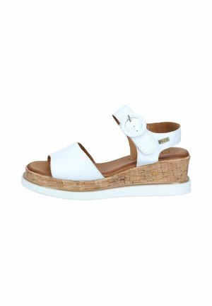White wedge sandal with cork sole, open toe, ankle strap featuring a round buckle, and a brown cushioned footbed.