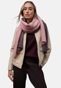 Giacca beige con zip, sciarpa rigata rosa e grigia, maglione borgogna e pantaloni scuri. Tessuto liscio, vestibilità comoda e design a strati.