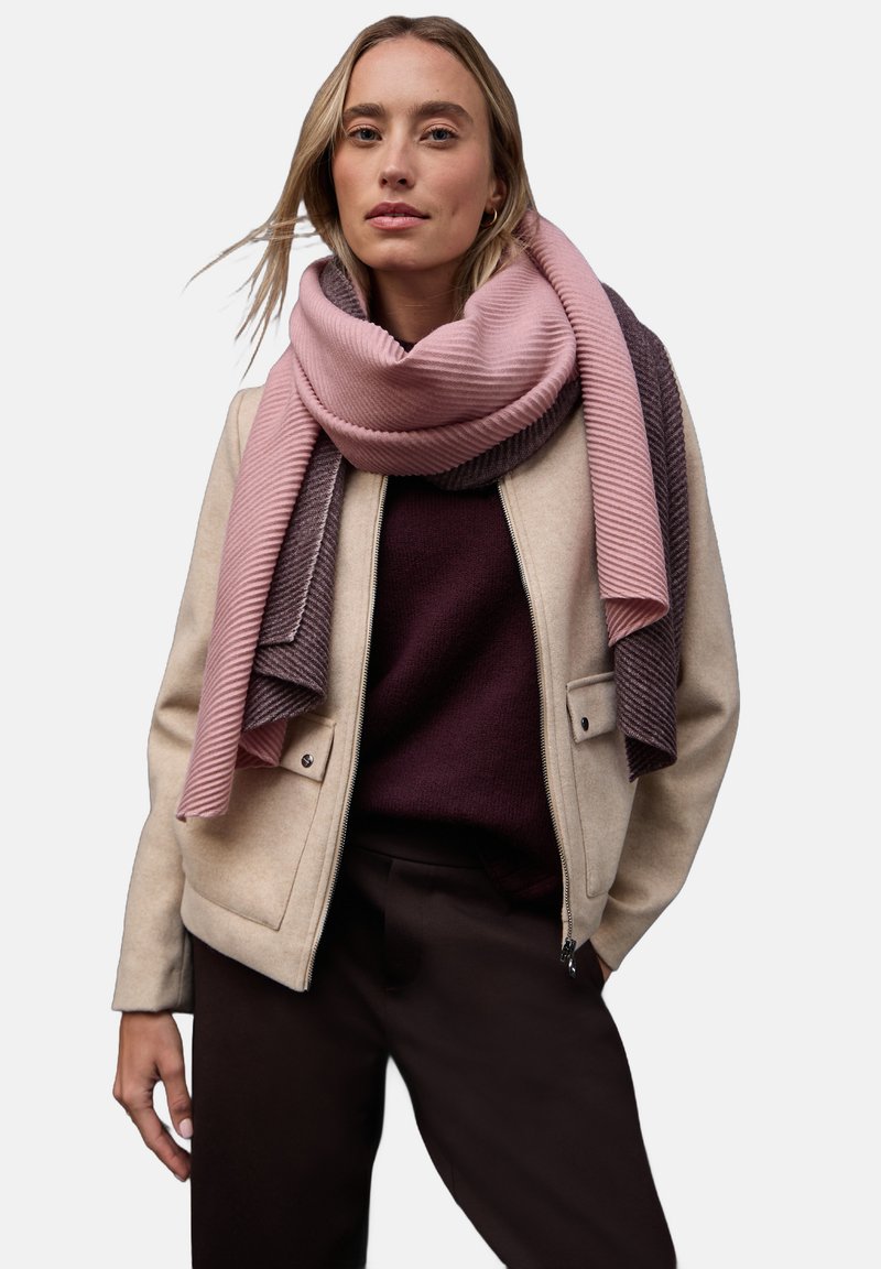 Giacca beige con zip, sciarpa rigata rosa e grigia, maglione borgogna e pantaloni scuri. Tessuto liscio, vestibilità comoda e design a strati.