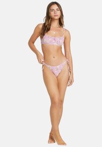 Pink bikini with floral pattern, featuring a cropped top and low-rise bottom with side ties. Crafted from smooth fabric, lightweight texture.