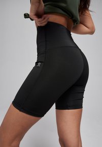 High-waisted black shorts made of stretchy fabric, featuring a snug fit, side stitching details, and a small logo on the thigh.