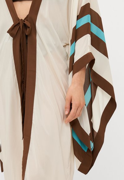 Kimono marron et crème avec un col en V et une fermeture par lien. Il présente de larges manches avec des rayures marron et turquoise. Tissu lisse et léger.