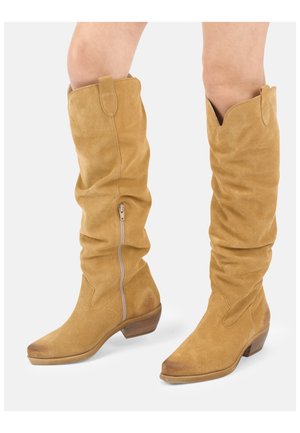 Tanfarvede ruskind knæhøje støvler med lave træhæle og en sidelås på hvid baggrund.