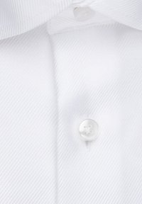 Witte overhemd met een fijne geribbelde textuur, voorzien van een ronde witte knoop en contrasterende stiksels langs de knoopsluiting.