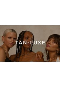 Drie vrouwen met verschillende kapsels, gekleed in eenvoudige, mouwloze tops. De tekst "TAN-LUXE" staat prominent in het midden weergegeven.