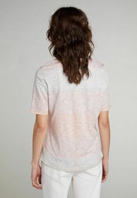 Camisa ligera de manga corta con un degradado de rosa suave y blanco, que presenta un acabado texturizado y costuras naranjas a lo largo de las costuras.