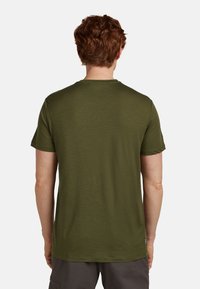 Olivově zelené tričko s krátkým rukávem, kulatým výstřihem, hladkou texturou, jednoduchým designem, se malou logo etiketou na spodním lemu.