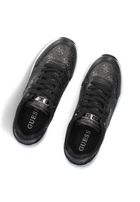 Zwarte sneakers van glanzend synthetisch materiaal, met een patroon op de bovenkant, vetersluiting en witte rubberen zool. Logo-accenten aan de zijkanten.