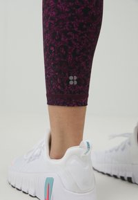 Leggings v temno vijolični barvi z dizajnom črnega leoparda, s manjšim logotipom na mečih in oprijetim, skrajšanim krojem.