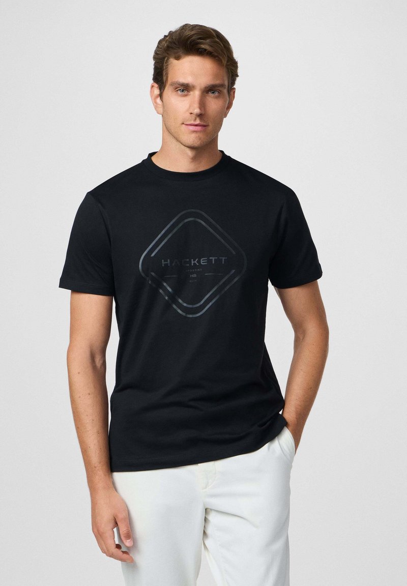 Camiseta negra de manga corta con un logotipo gráfico en forma de diamante en gris con la palabra "HACKETT". Corte clásico, textura suave y cuello redondo.