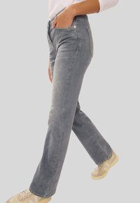 Grijze denim jeans met een recht gesneden ontwerp, vijf zakken en subtiele vervaging. Gecombineerd met beige sneakers voor een casual look.