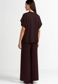 Burgundy two-piece outfit featuring a loose-fitting, short-sleeve top and wide-leg pants, made from soft, textured fabric.