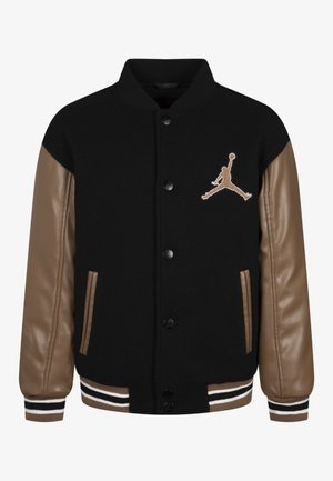 Sort varsity-jakke med brune læderærmer, knaplukning foran, stribede manchetter og en brun Jumpman basketball-logo på brystet.