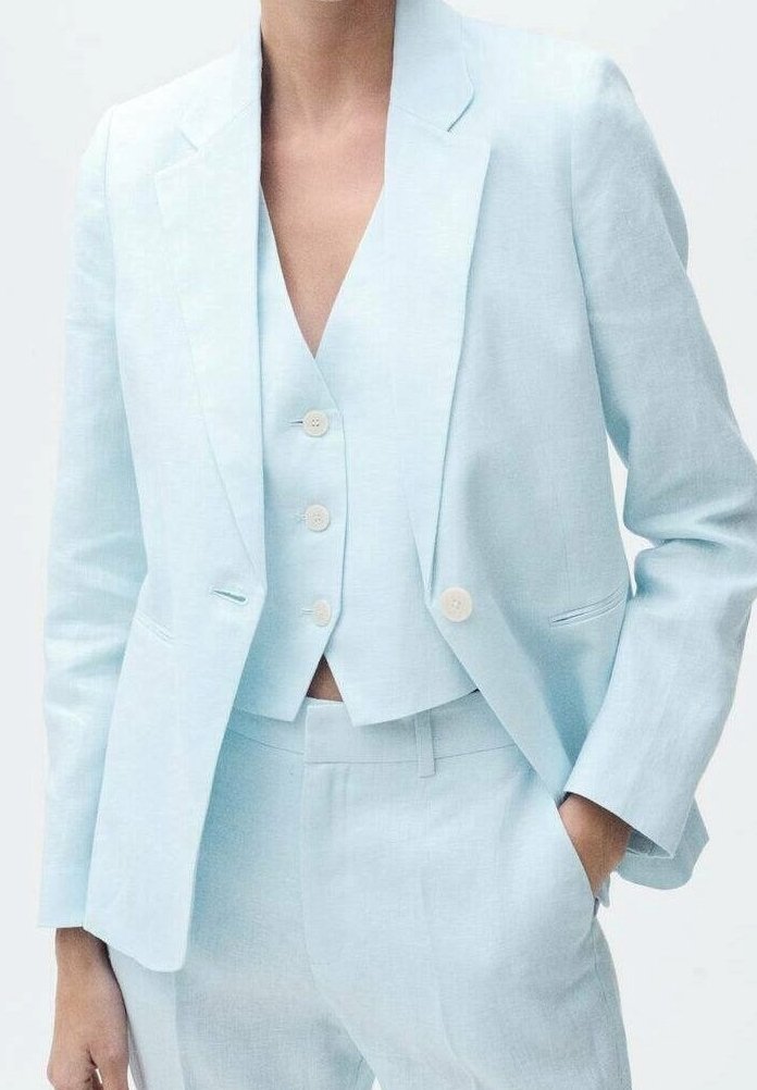 Costume en lin bleu clair composé d'un blazer cintré à revers crantés, d'un gilet court à deux boutons et d'un pantalon sur mesure à texture lisse.