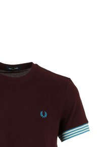 T-shirt bordeaux avec un col rond, présentant un logo bleu brodé sur la poitrine gauche et des accents rayés bleus et blancs sur les manches.