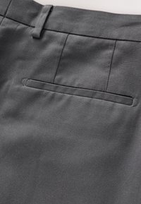 Pantalon en tissu gris avec une texture lisse. Comprend une poche arrière avec un ourlet discret et un design à l'avant plat.