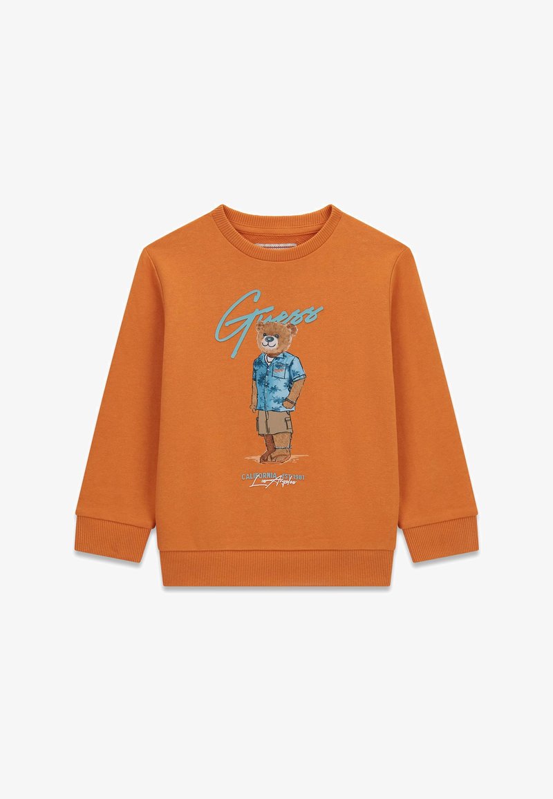 Sweat-shirt orange à manches longues avec un ours en peluche portant une chemise bleue et un short beige imprimé sur le devant, accompagné du texte "Guess" au-dessus.