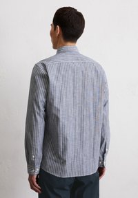 Striped button-up shirt in blue and white; features long sleeves, a collar, and rounded hem with buttoned cuffs. Textured fabric.
