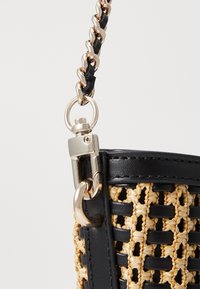 Sac à main tissé noir et jaune avec une bandoulière chaîne dorée brillante, orné d'accents en cuir et d'un fermoir métallique.