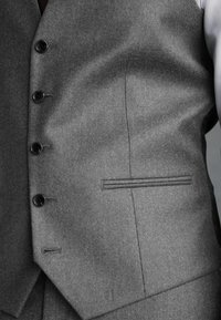 Chaleco de traje de lana gris que presenta cinco botones negros, un diseño elegante y una textura sutil, con un bolsillo lateral y costuras cuidadas.