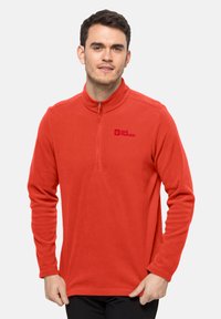 Pullover in pile rosso con colletto a mezza zip. Presenta maniche lunghe e un logo sul lato sinistro del petto. Tessuto morbido, vestibilità casual.