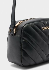 Schwarze gesteppte Leder-Umhängetasche mit goldfarbener Reißverschluss und "LIU JO"-Logo, ausgestattet mit einem schlanken Schulterriemen und Zickzackmuster.