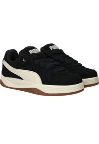 Sneaker in suede nera con accenti bianchi, dotate di linguetta imbottita, spesse stringhe nere e suola in gomma marrone con texture.