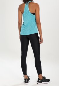 Ljusblå atletisk tanktop med racerbaksdesign, kombinerad med svarta leggings och svarta löparskor med vita sulor.