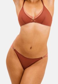 Brun bikini-sæt med en trekantet bralette med en cirkulær detalje og matchende lavtaljede trusser. Glat stof med glansdetaljer.