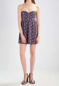 Robe sans bretelles avec un motif en chevrons dans des nuances de bleu marine, rose et blanc. Confectionnée en tissu léger, avec un ourlet évasé.