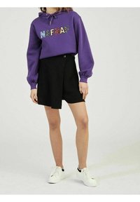 Violetti huppari, jossa monivärinen "NAFNAF"-kirjailu, yhdistetty mustaan kietaisuhameeseen ja valkoisiin lenkkareihin. Pehmeää kangasta, rento malli, pitkät hihat.