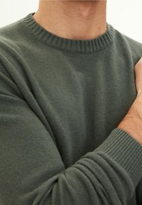 Maglione verde scuro con collo e polsini a coste, trama a maglia, maniche aderenti e finitura del tessuto liscia.