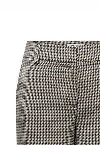 Pantaloni a motivo in pied de poule neri e beige, con vita aderente, passanti per la cintura e due tasche frontali. Dettagli in tessuto testurizzato visibili.