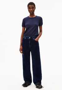 Navy katoenen t-shirt gecombineerd met brede navy corduroy broek met subtiele verticale lijnen en een tailleband met knoopsluiting.