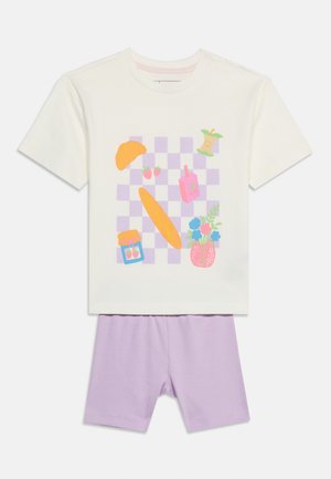 Cremefarvet kortærmet skjorte med pastelfarvet lilla ternet mønster og illustrationer af croissant, jordbær, baguette, krukke, juice, æblekerne og blomster, kombineret med lyse lilla shorts.