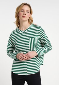 Camicia a maniche lunghe a righe verdi e bianche con colletto e taschino sul petto. Realizzata in tessuto morbido con un taglio comodo.