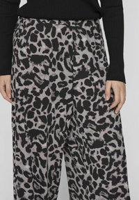 Hlače s leopard printom u crnoj i sivoj boji, s opuštenim krojem i glatkom teksturom, sa bočnim džepovima i elastičnom gumom u struku.