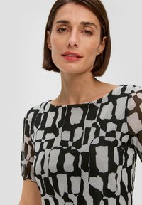 Zwart-wit gebloemde blouse met een ronde halslijn, doorzichtige mouwen en een abstracte print met onregelmatige vormen en een gestructureerde afwerking.