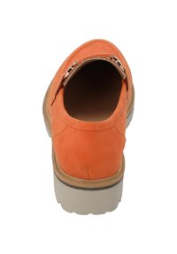 Zapato de ante naranja tipo deslizador con punta redonda, que presenta una hebilla metálica y una suela de goma beige. Textura suave y diseño sencillo.