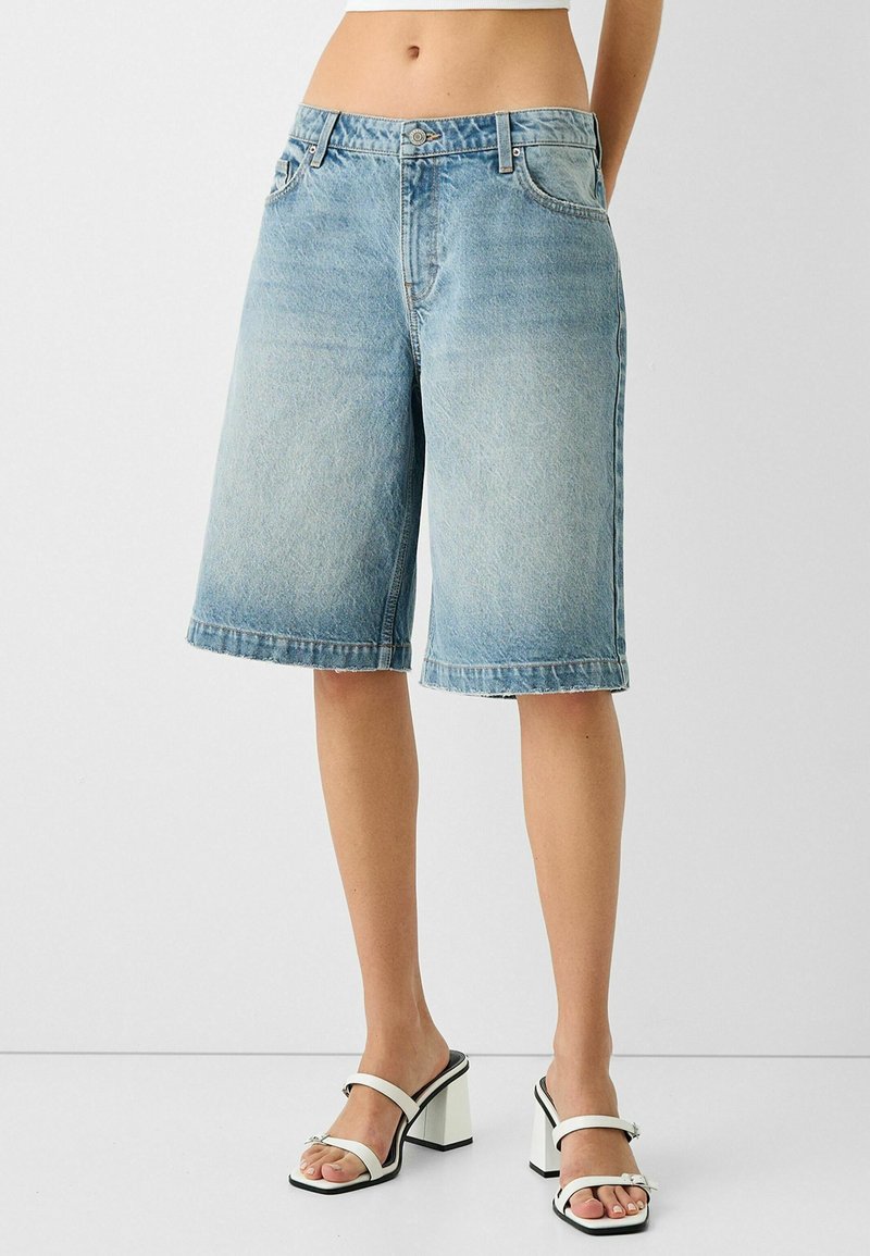 Ljust blå denim bermudashorts med rak passform, femfickorsdesign och fransad fåll. I kombination med vita sandaletter med blockklack.