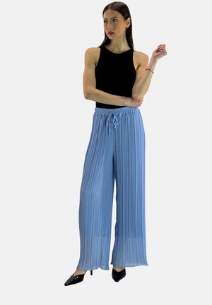 Lichtblauwe plisségroene wijde broek met elastische tailleband en trekkoord, gecombineerd met een zwart aansluitend tanktopje en zwarte hakken.