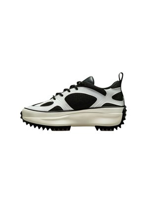 Zwart-witte sneaker van mesh en glad leer, met een dikke zool met puntige spikes en een trekband op de hiel.