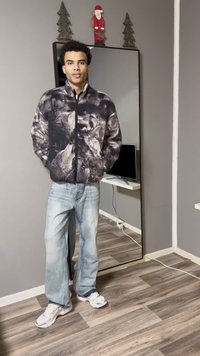 Ζακέτα από φλις με τύπωμα λύκου σε μαύρο και γκρι, κλείσιμο με φερμουάρ και πλαϊνές τσέπες· συνδυασμένη με ανοιχτό μπλε τζιν με φθορές και λευκά αθλητικά παπούτσια.