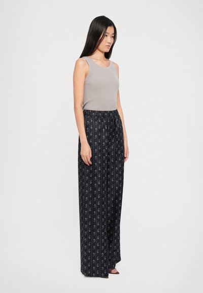 Graues, geripptes Tanktop kombiniert mit navyblauen, weit geschnittenen Hosen, die ein kleines, weißes Paisleymuster und einen elastischen Bund aufweisen.